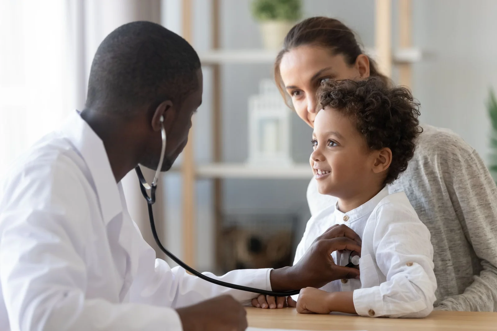 Physician examining a child with stethoscope while the mother watches - FirstCare Urgent Care accepts most major insurance plans